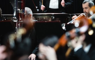 mężczyzna w garniturze i białek kuszuli trzyma w rękach pałki do kotłów