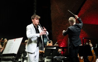 mężczyzna w jasnym garniturze grana klarnecie