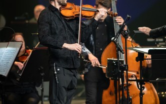 mężczyzna grający na skrzypcach, za nim mężczyzna grający na kontrabasie