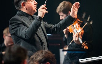 mężczyzna z uniesioną ręką, w której trzyma batutę