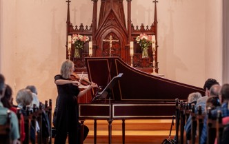 kobieta grajaca na skrzypcach, zza nia stoi klawesyn