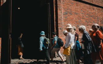 grupa turystów idąca z prawej strony w stronę drzwi katedry, znajdujących się z lewej strony fotografii