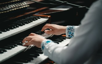 zbliżenie na dłonie i ręce mężczyzny grającego na potrójnej klawiaturze organów