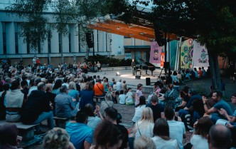 na pierwszym planie liczna publiczność, z tyłu scena i solista