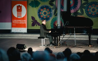 w dolnej części publiczność, w centralnej solista grający na fortepianie