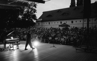 Solista stoi na scenie przed publicznością, która wypełnia całą widownię