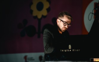 zbliżenie na solistę, ukazany delikatnie od boku, od pasa w górę