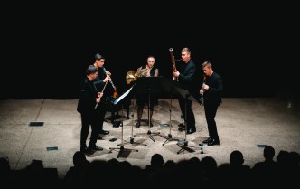 czworo mężczyzn i kobieta grających na instrumentach dętych