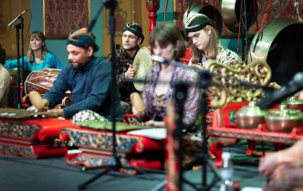osobysiedzące na podłodze i grające na instrumntach muzycznych