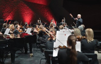 orkiestra na scenie i dyrygent z uniesionymi rękoma 