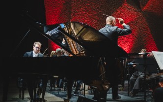 mężczyzna frający na fortepianie i mężczyzna z uniesinymi rękoma - dyrygent