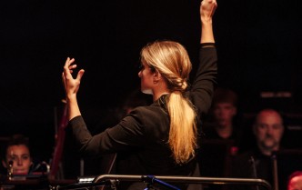 kobieta stojąca tyłek trzyma ręce w górze, w prawej dłoni trzyma batutę