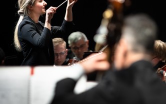 kobita trzymająca usienione ręce, w jednej trzyma batutę