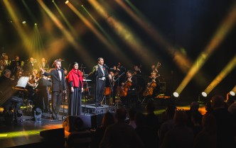 orkiestra, soliści i dyrygent na scenie stojący przodem do publiczności