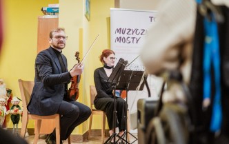 siedzący mężczyzna trzyma skrzypce