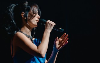 kobieta w niebieskiej sukni śpiewa do mikrofonu