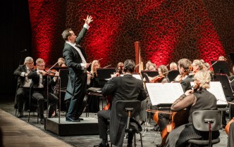 mężczyzna z podniesioną wysoko lewą ręką - dyrygent