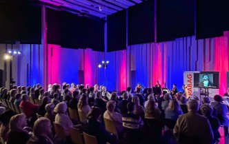 słuchacze na widowni widziani z tyłu sali, w tle siedzący muzycy