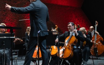 mężczyzna w czarnym garniturze trzyma uniesioną lewą rękę