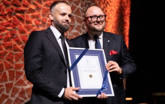 dwóch mężczyzn trzymających oprawiony w ramę dyplom