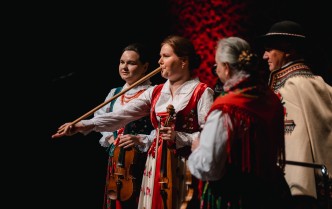 kobiety i mężczyzna w strojach góralskich grają na instrumentach muzycznych