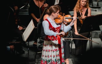 kobieta w góralskim stroju ludowym gra na skrzypcach