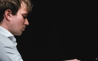 zbliżenie na pianistę w białej koszuli z dłońmi na klawiaturze, mężczyzna ukazany jest z profilu