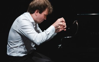  pianista w białej koszuli z dłońmi nad klawiaturą, mężczyzna ukazany jest z profilu