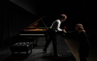pianista przed fortepianem pochyla się i odbiera od kobiety z publiczności różę