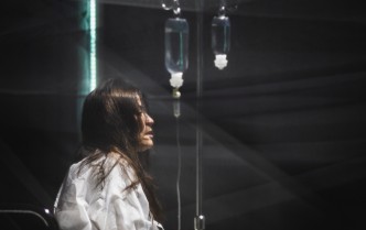 kobieta siedząca na łóżku szpitalnym, na stelażu wiszą kroplówki
