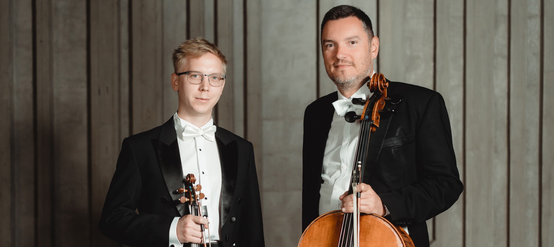 dwóch mężczyzn trzymających instrumenty smyczkowe