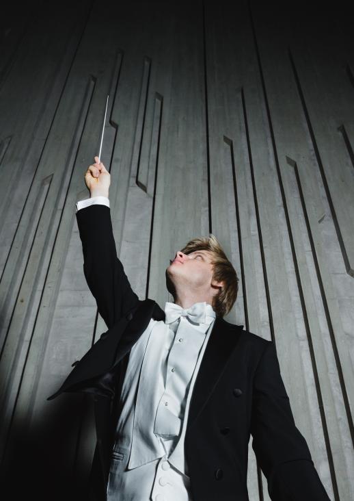 a young man holding a baton in his hands pointing upwards