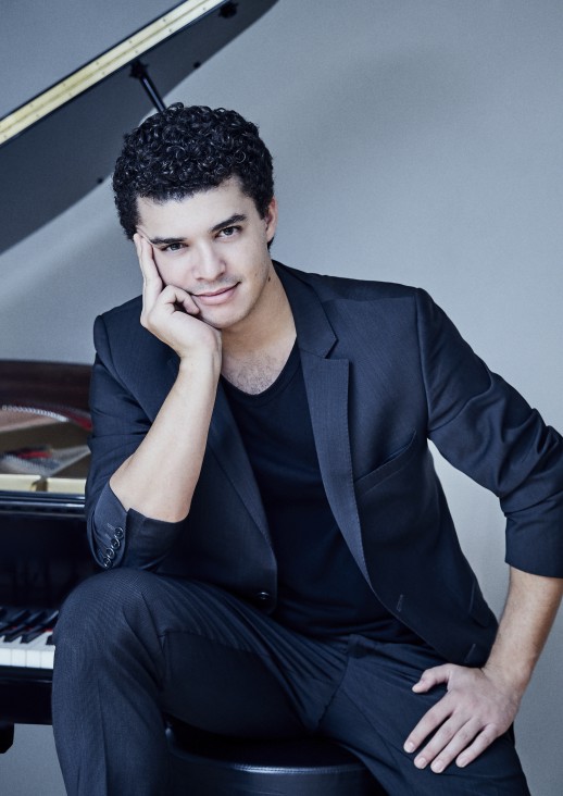 młody ciemnowłosy mężczyzna siedzący obok fortepianu