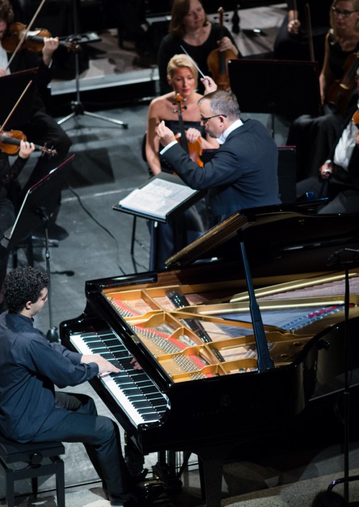 a man playing the piano and a conductor with his hands raised