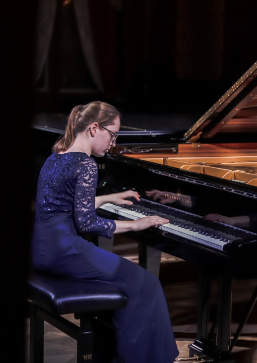 young woman in a blue dress playing the piano