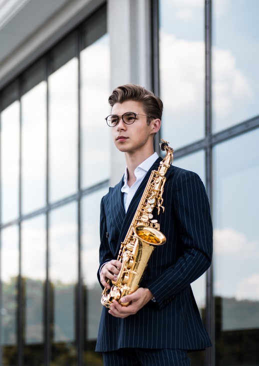 man with glasses holding a saxophone