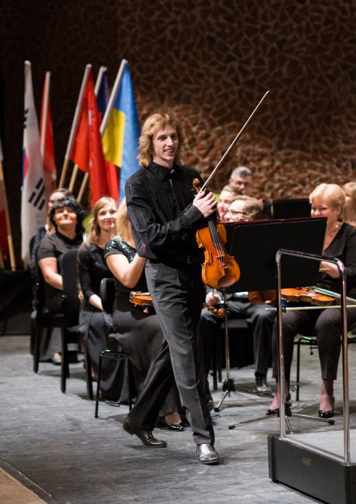 mężczyzna na scenie ze skrzypcami i smyczkiem w ręce