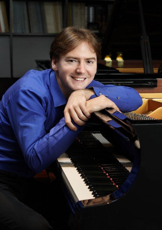 siedzący mężczyzna opiera się o fortepian