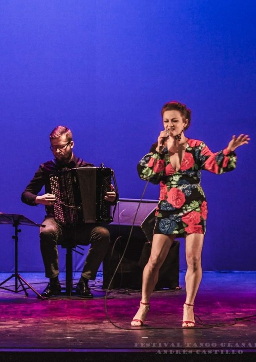 mężczyźni grający na skrzypcach i akordeonie oraz kobieta śpiewająca do mikrofonu