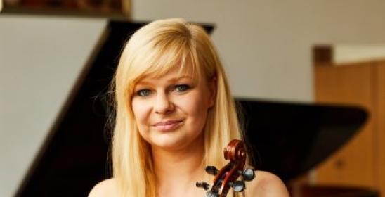 young blonde woman in a black dress with bare shoulders holding a violin in her hands
