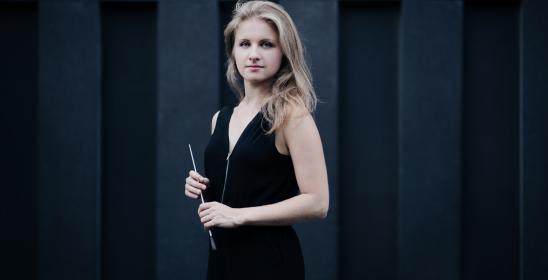 młoda kobieta, blondynka w czarnej bluzce trzymająca batutę w dłoniach