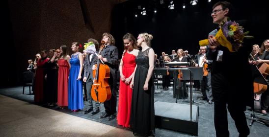 młodzi ludzie w eleganckich strojach stojący w szeregu