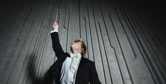 a young man holding a baton in his hands pointing upwards