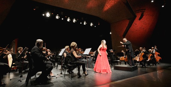 śpiewaczka w czerwonej sukni i orkiestra na scenie