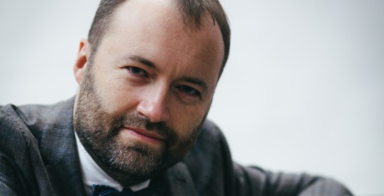 portrait of a man leaning against a piano