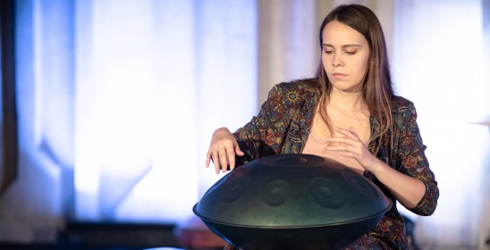 siedząca kobieta gra na instrumencie muzycznym handpan