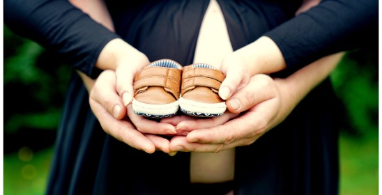 dłonie mężczyzny i kobiety trzymające buciki dziecięce