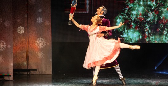 dziewczynka z uniesioną nogą trzyma lalkę w ręce, za nią stoi starszy mężczyzna - para baletowa