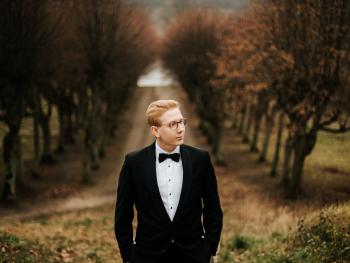 a young man with fair hair standing on a forest road