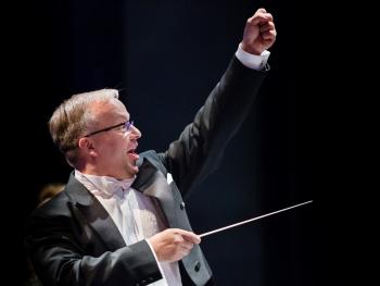 a man in a tailcoat with a baton and a raised hand